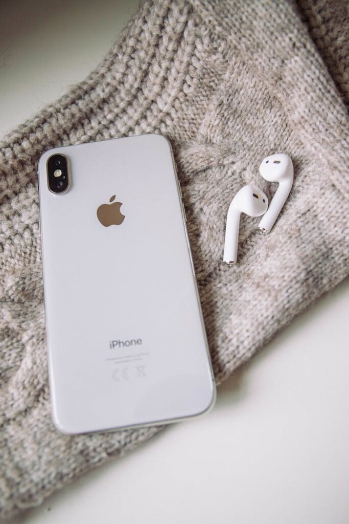 Close-up of Apple iPhone and AirPods placed on a cozy knit fabric for a modern tech lifestyle representation.